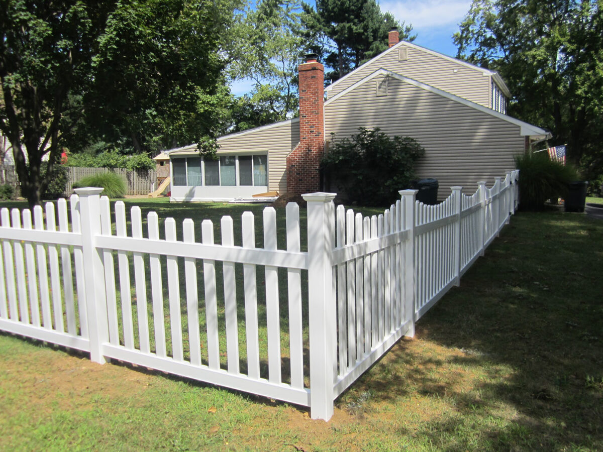 white vinyl concaved picket fence with post caps in yard