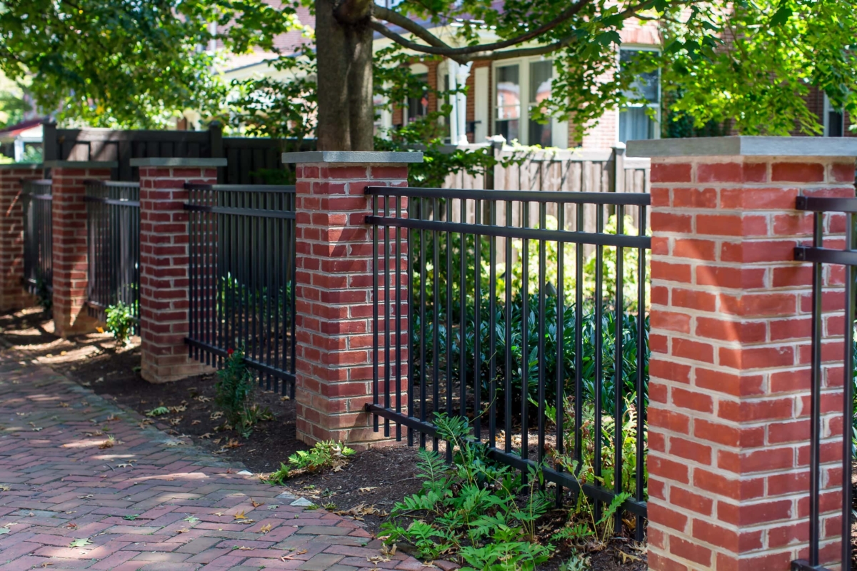 black metal fence between brick pillars
