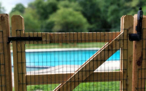 wood split rail gate with wire mesh around swimming pool