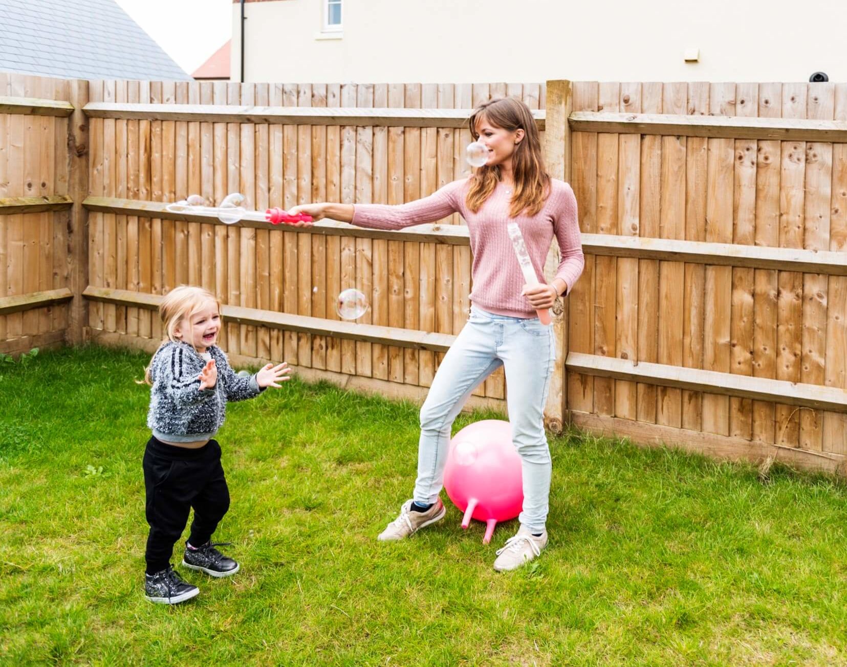 Parent and child playing in fenced yard