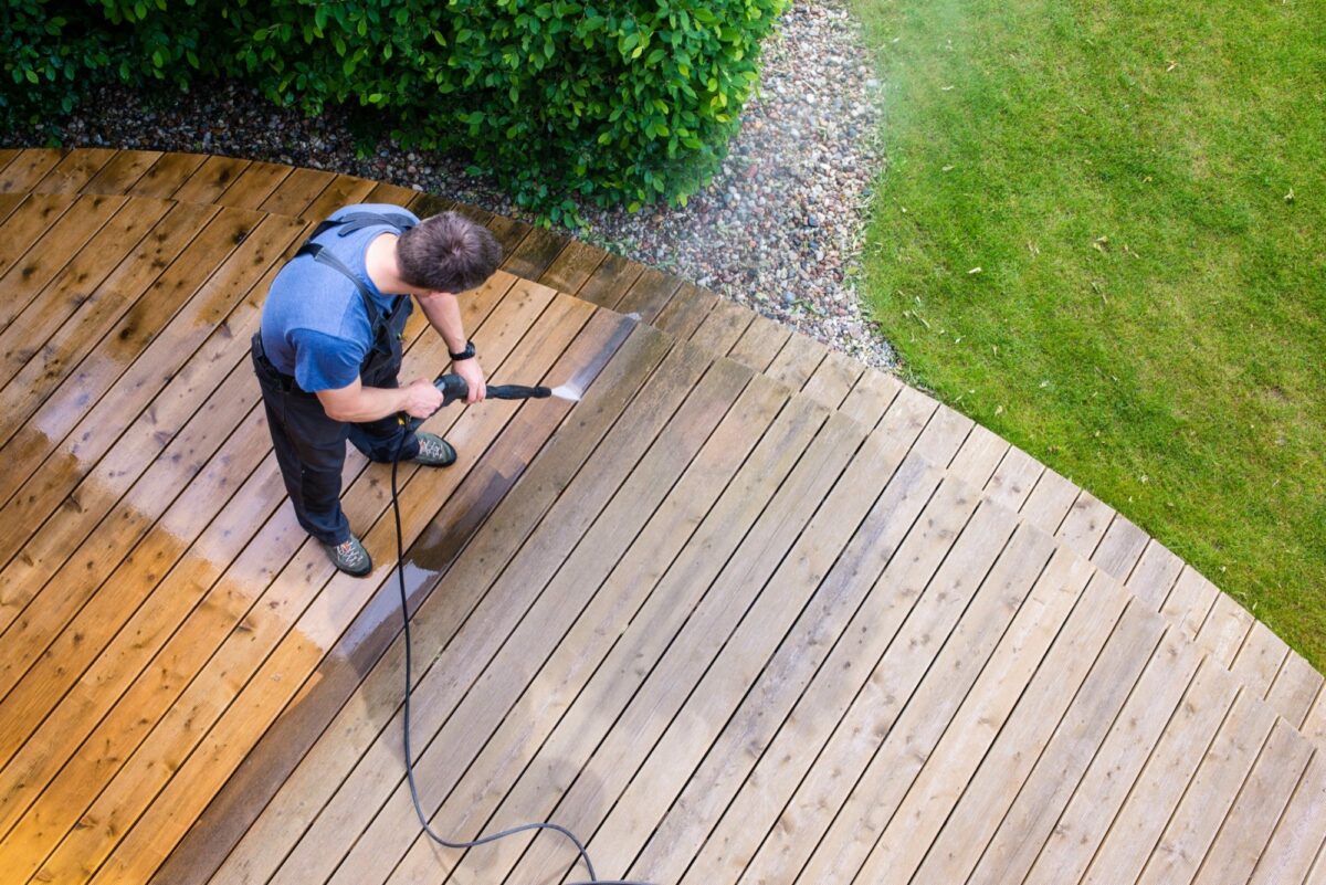 Professional power washer cleaning a wooden deck